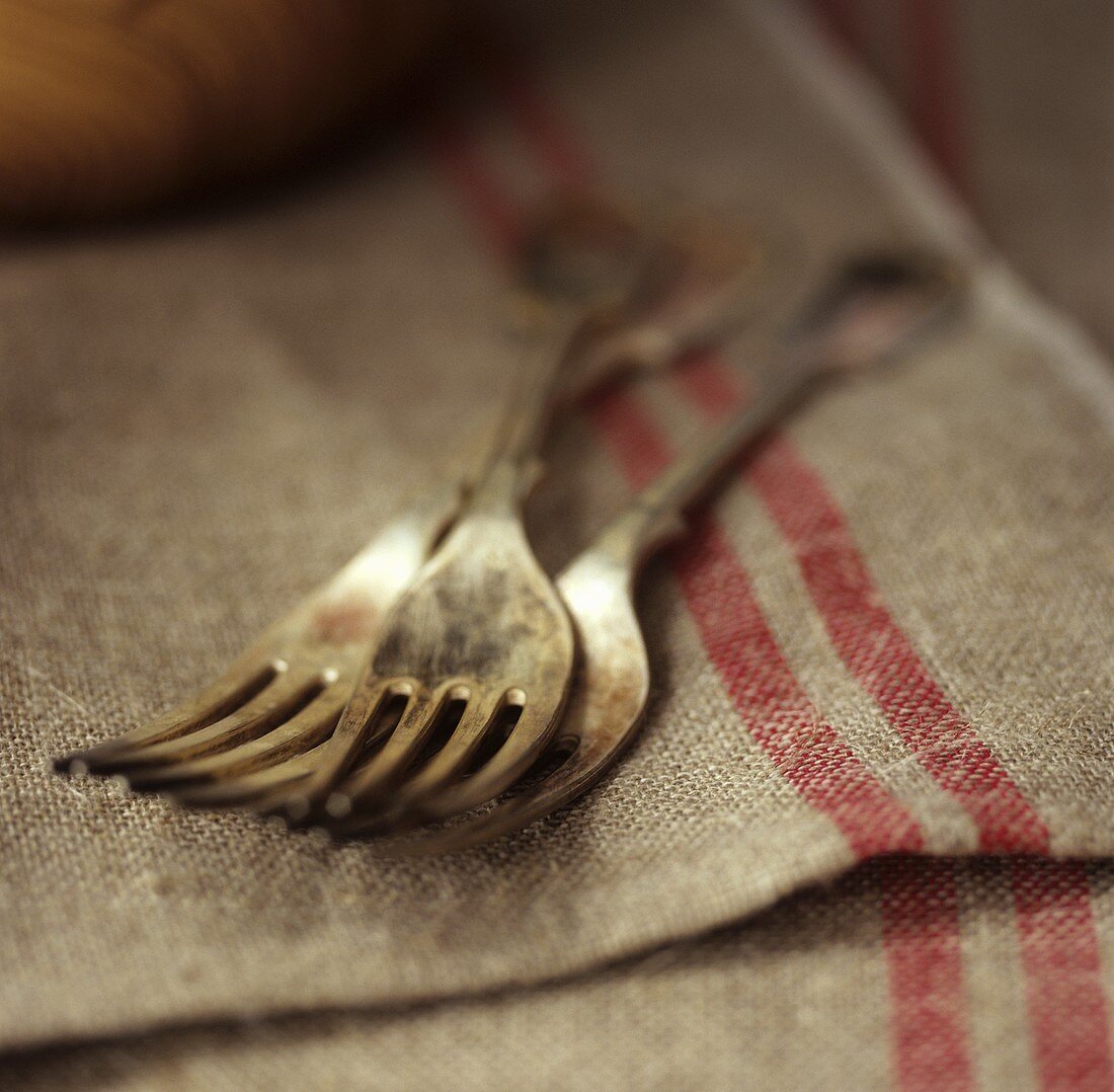 Three silver forks on old linen cloths