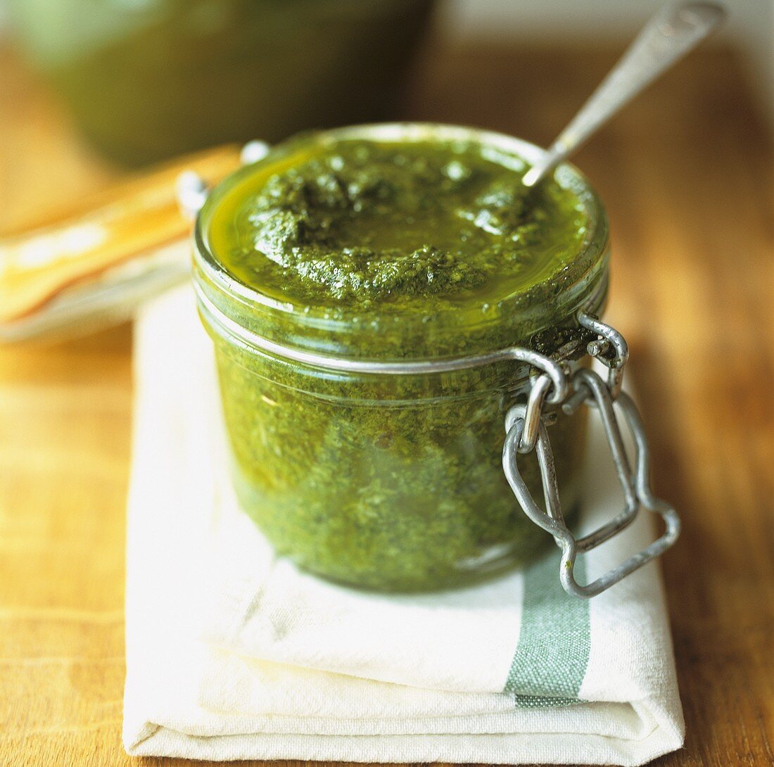 Pesto in einem Einmachglas mit Löffel auf einem Leinentuch