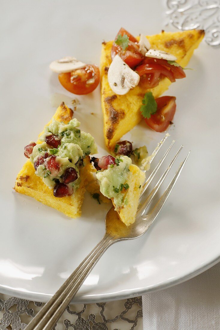 Polenta slices topped with avocado cream and tomatoes