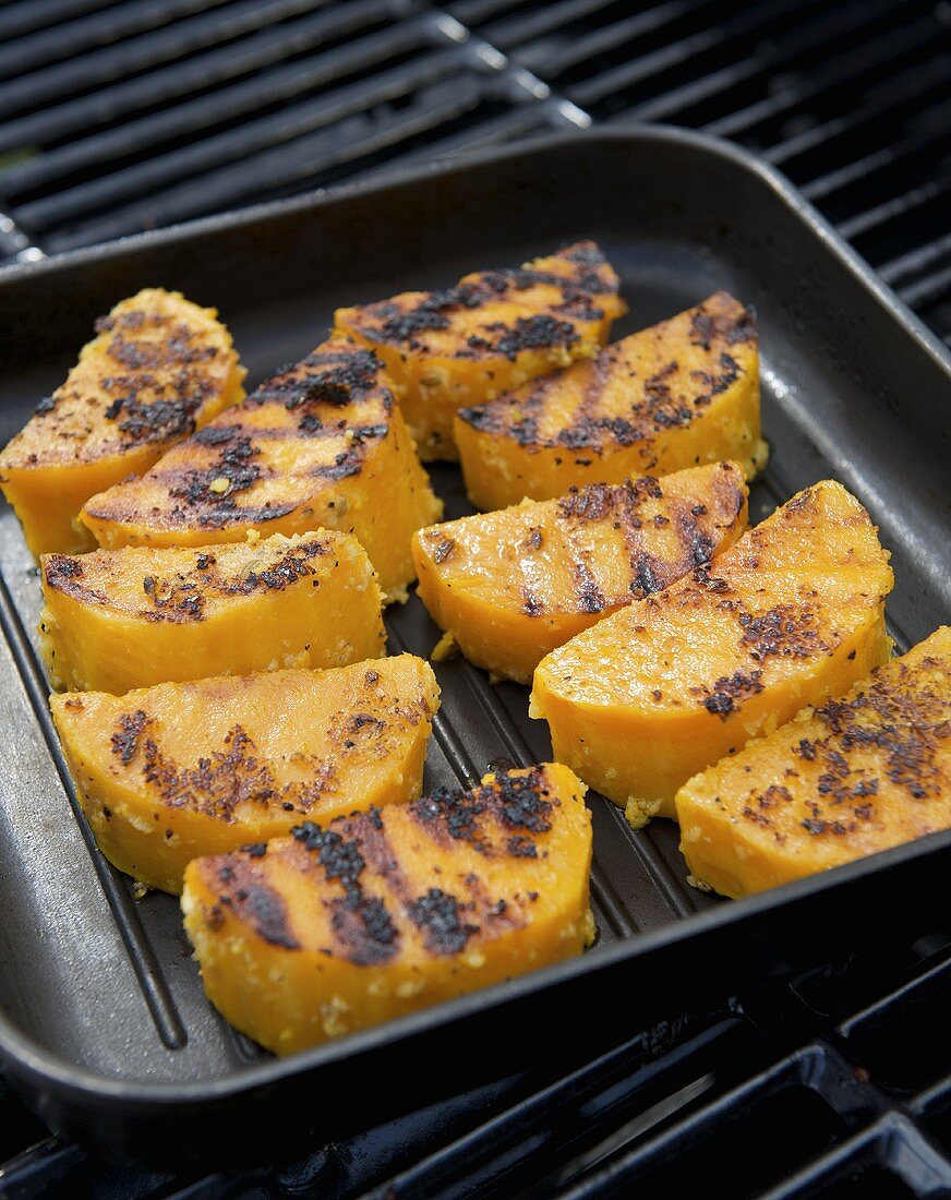Pieces of pumpkin in a grill frying pan on a grill