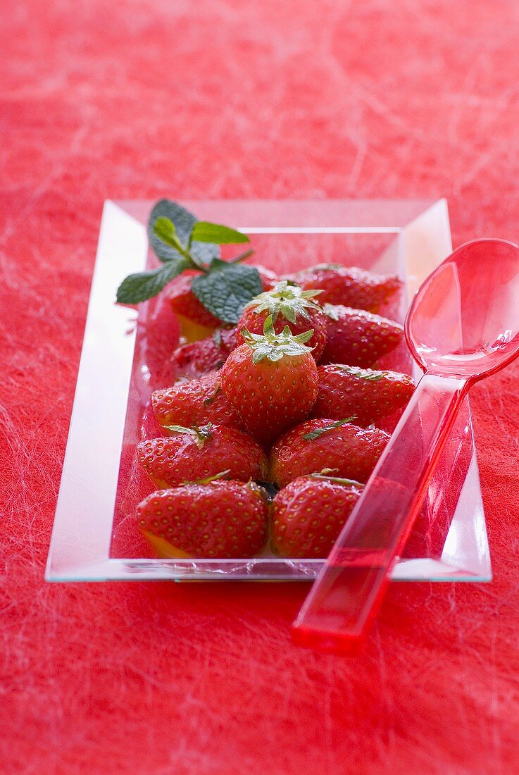 Erdbeer-Orangensalat mit Minze auf einem Glasteller
