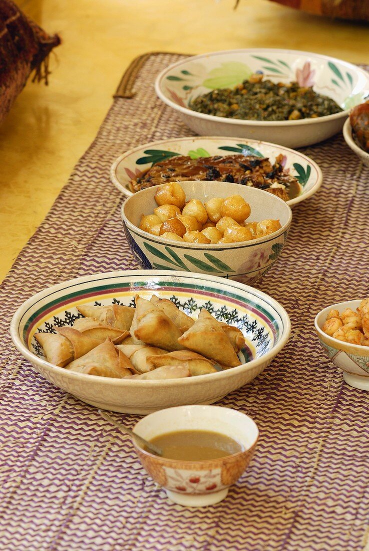 Several African foods in dishes on a carpet