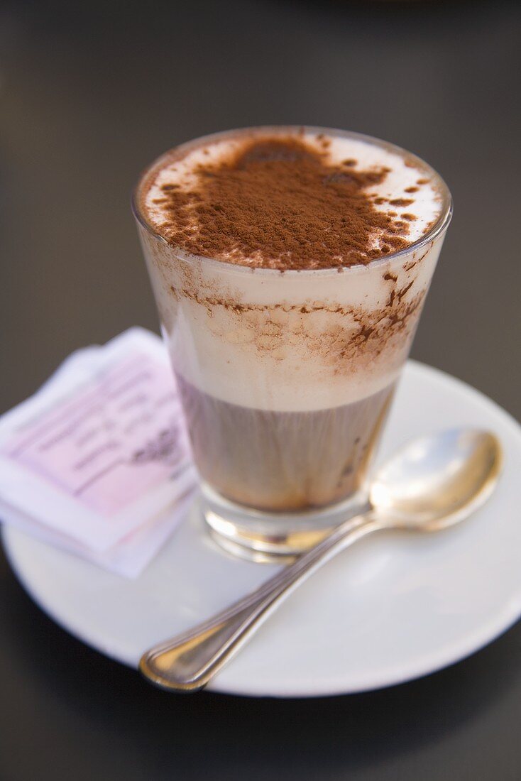 Ein Glas Cappuccino mit Kakao bestäubt