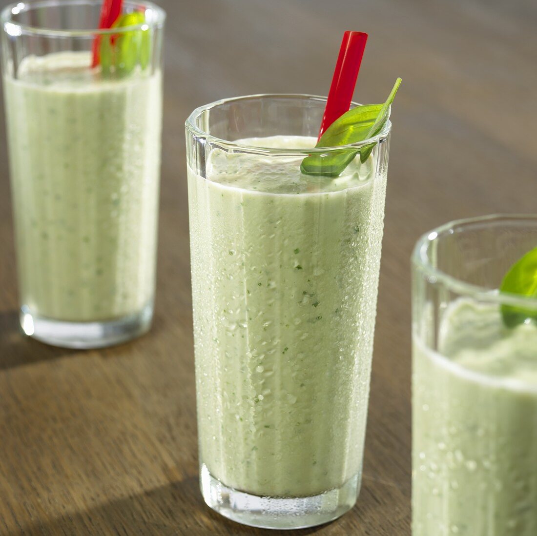 Cold cucumber and basil soup in three glasses with straws