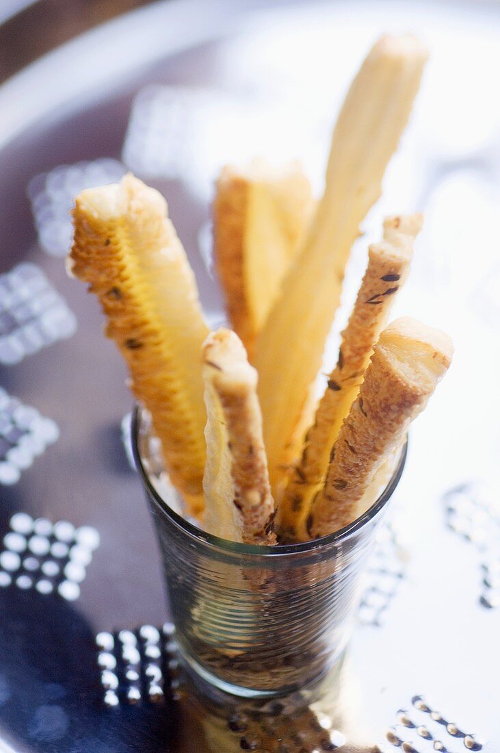 Puff pastry straws with Parmesan and cumin in a glass