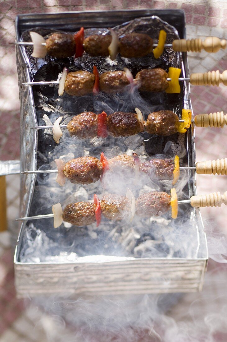Kefta-Spiesse auf einem rauchenden Holzkohle-Grill (Marokko)