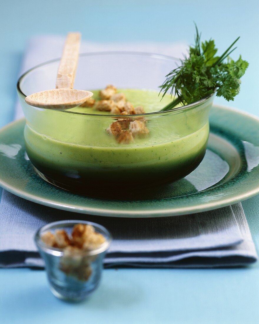 Cucumber and herb soup with croutons in a glass bowl