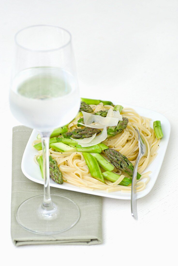 Tagliatelle mit grünem Spargel und Parmesan, danbeneb ein Glas Wasser