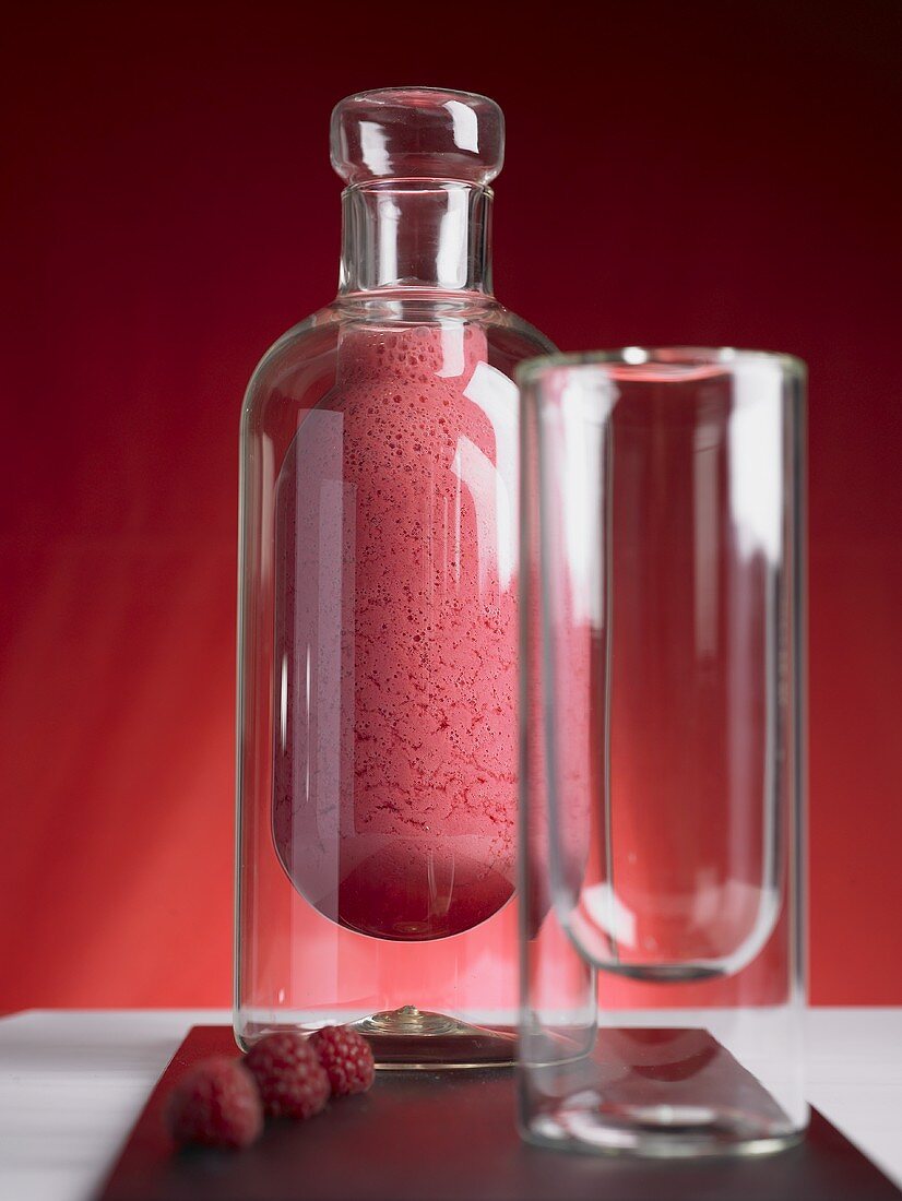 Himbeer-Pfirsich-Smoothie in einer Glasflasche mit Glas