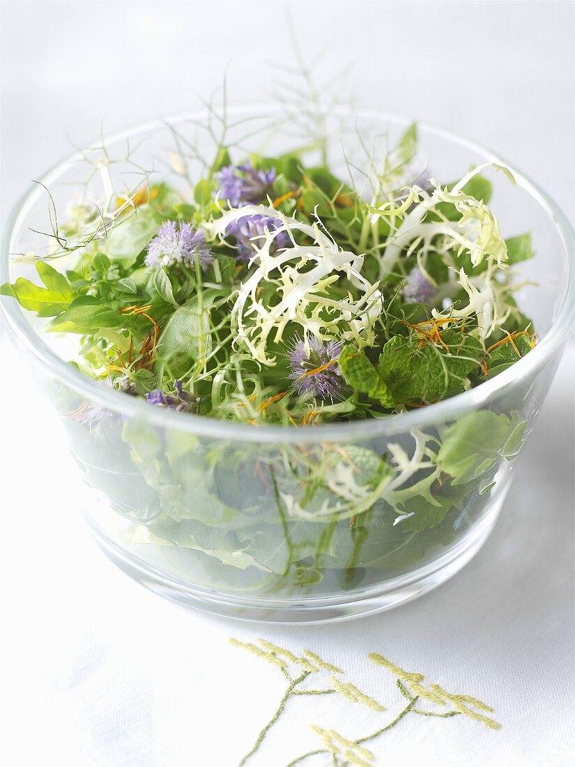 Kräutersalat mit Essblüten in einer Glasschale