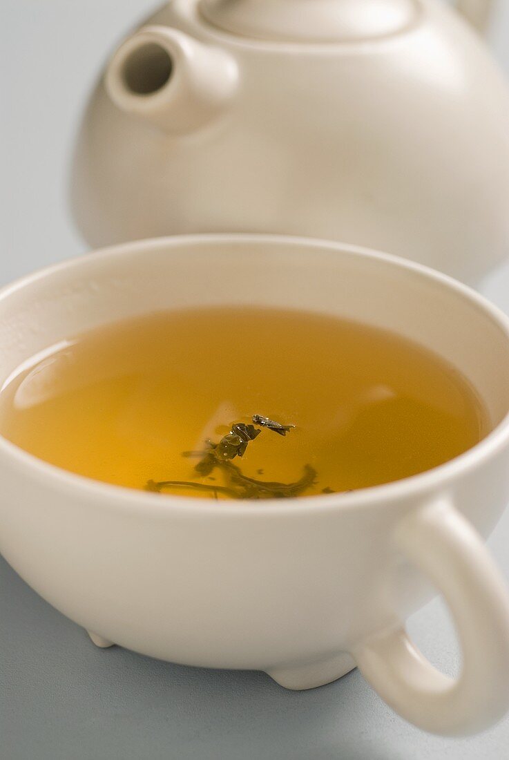 A cup of green tea with a teapot