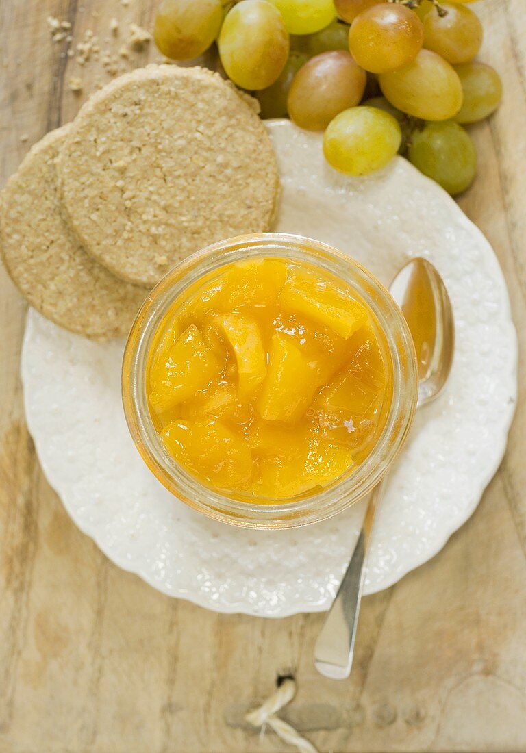 Mango-Ingwer-Chutney in einem Glas mit Haferkeksen, Trauben