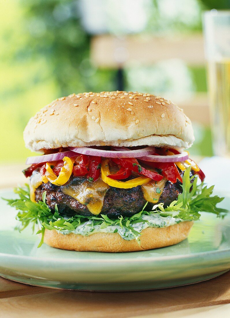 Burger with herb sauce, chutney, peppers and onions