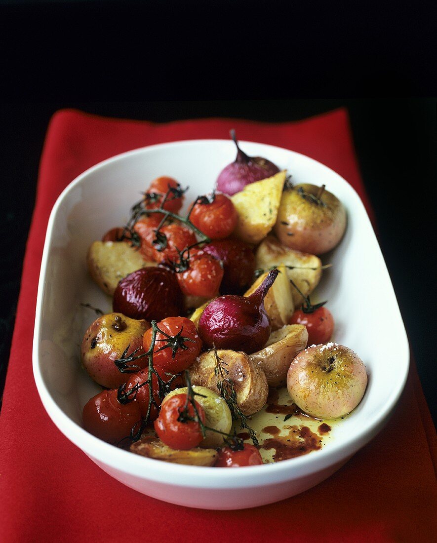 Gebackene Zwiebeln, Tomaten, Kartoffeln und Äpfel auf Platte