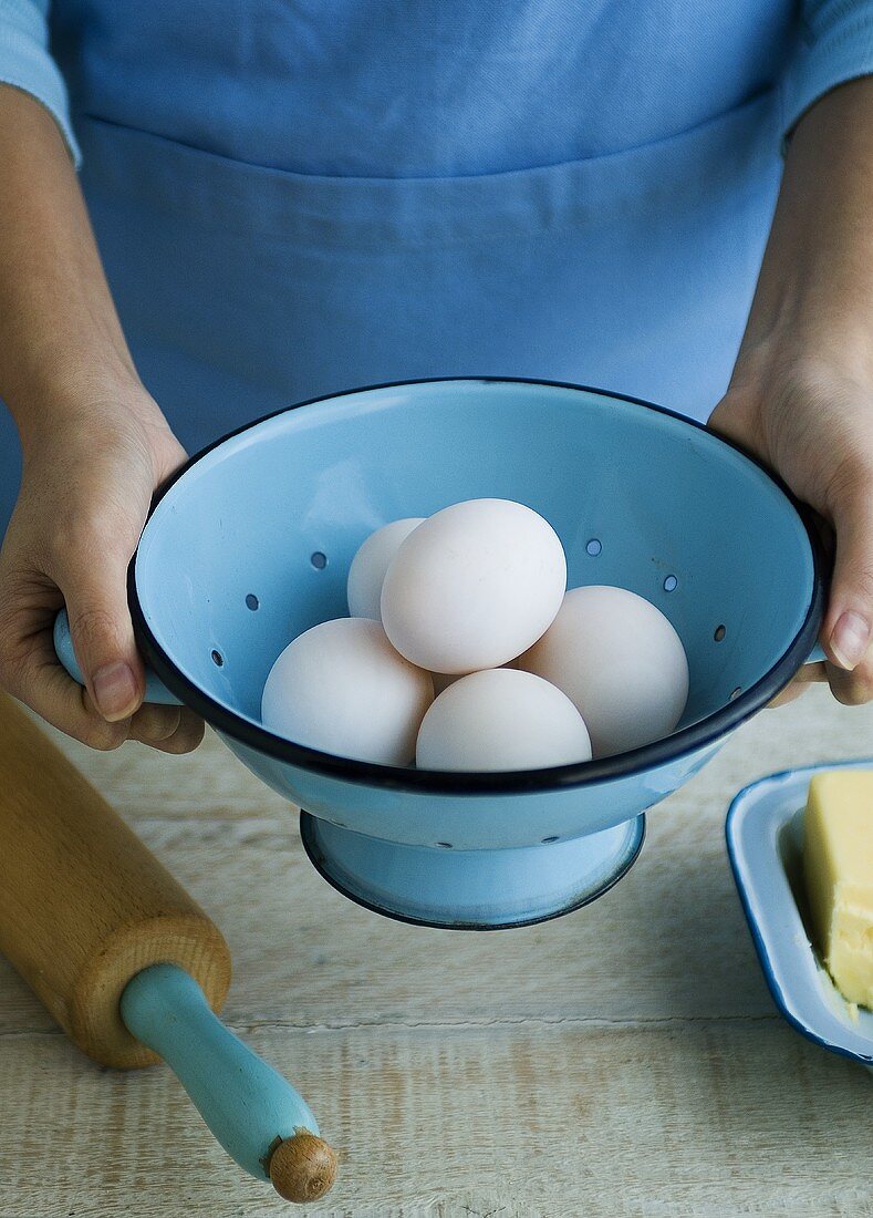Woman holding a colander half-full of eggs in her hands