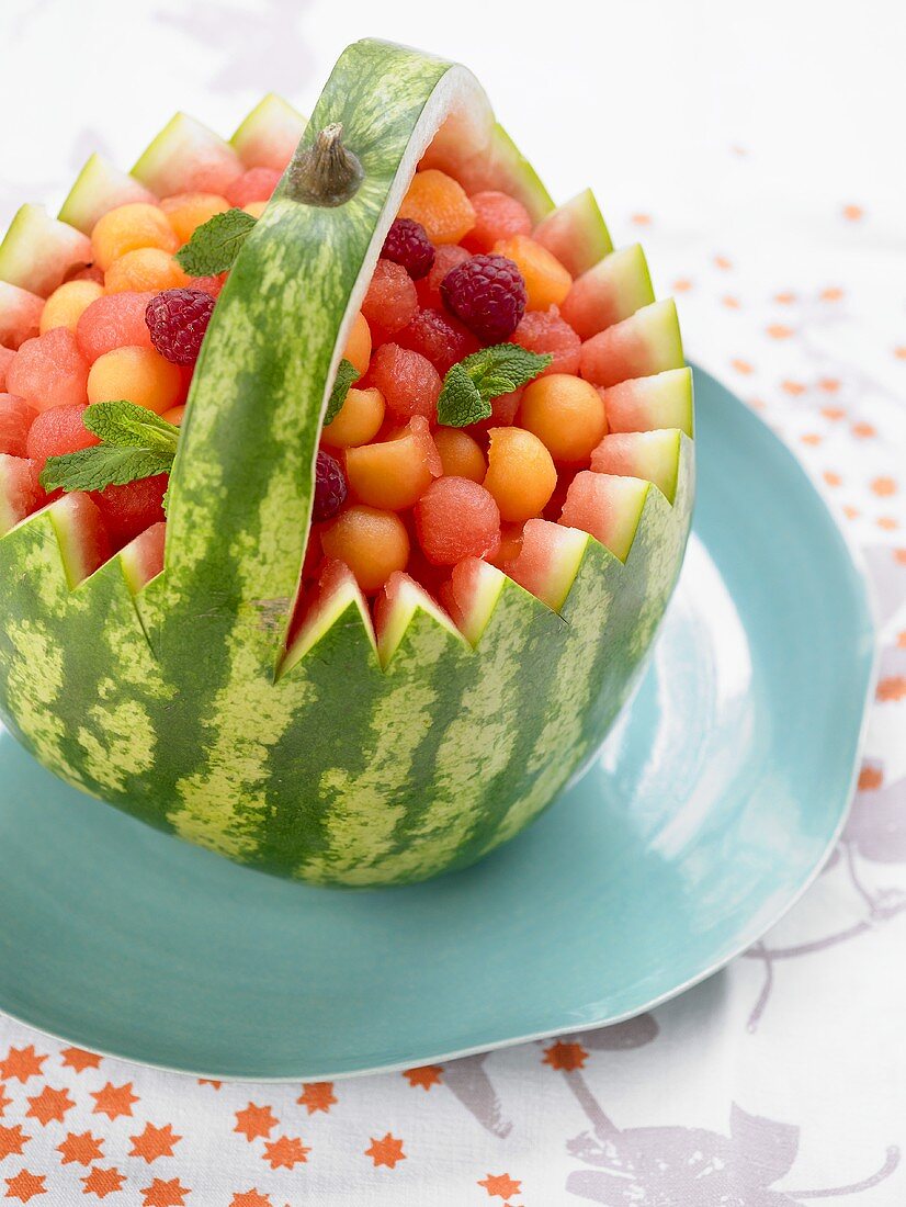 Watermelon basket filled with melon balls and raspberries