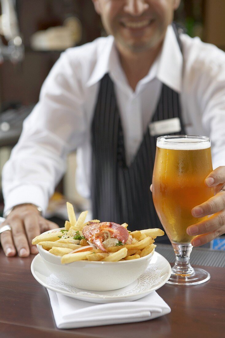 Lobster poutine with a glass of beer on a counter (Canada)