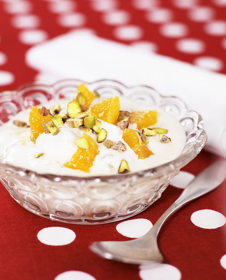 Yoghurt with orange segments & pistachios in a glass bowl