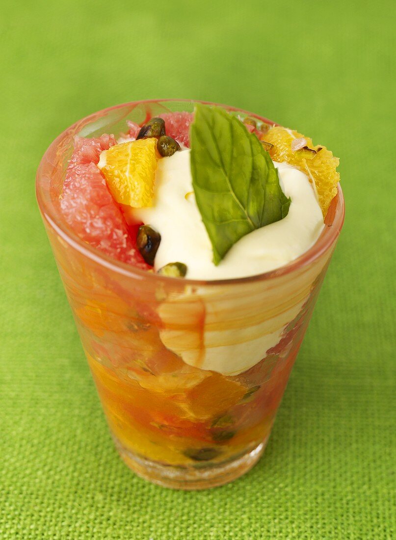 Citrus fruit salad with whipped cream & pistachios in glass