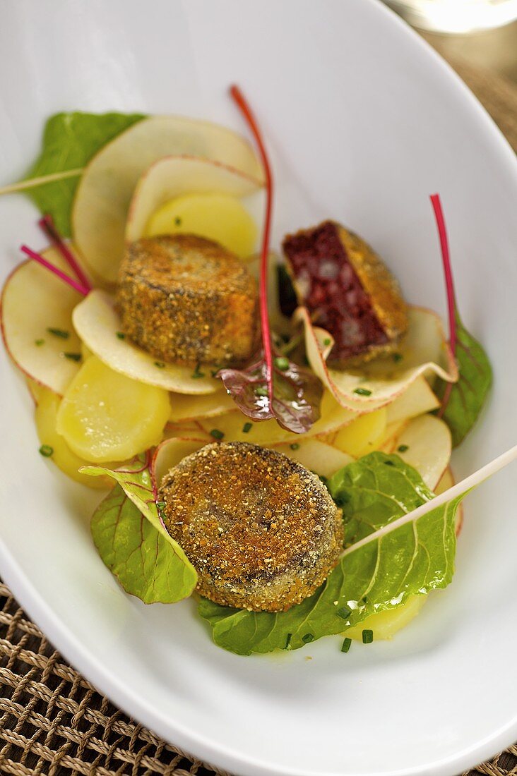 Black pudding slices in pumpkin seed coating, potato & apple salad