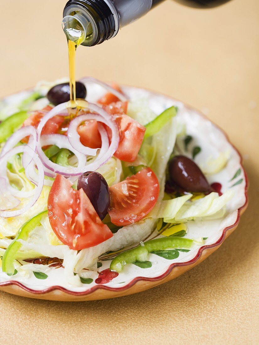 Mediterraner Salat wird mit Olivenöl begossen