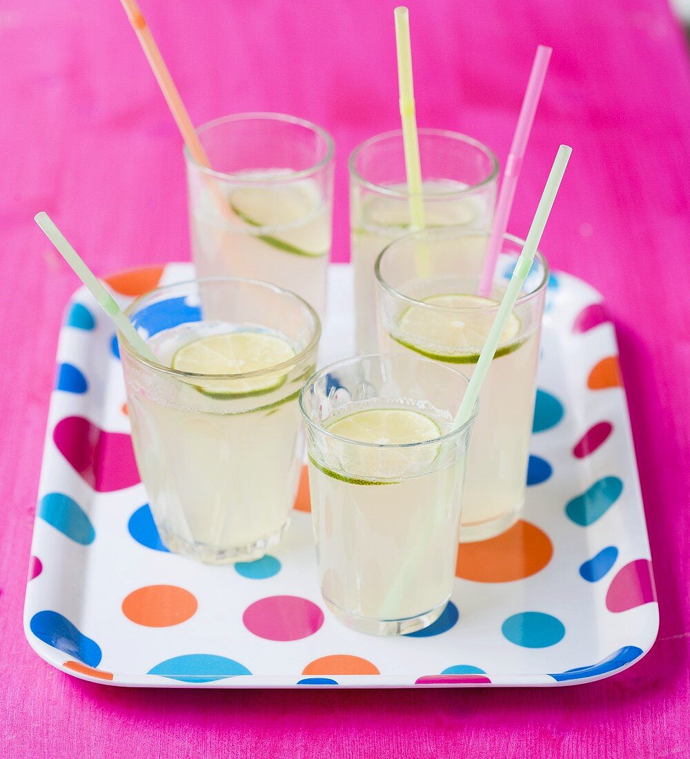 Five glasses of lemonade with straws on spotted tray
