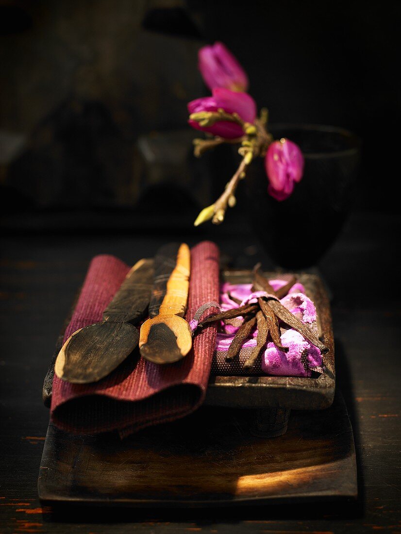 Vanilla pods with wooden cutlery on a wooden board