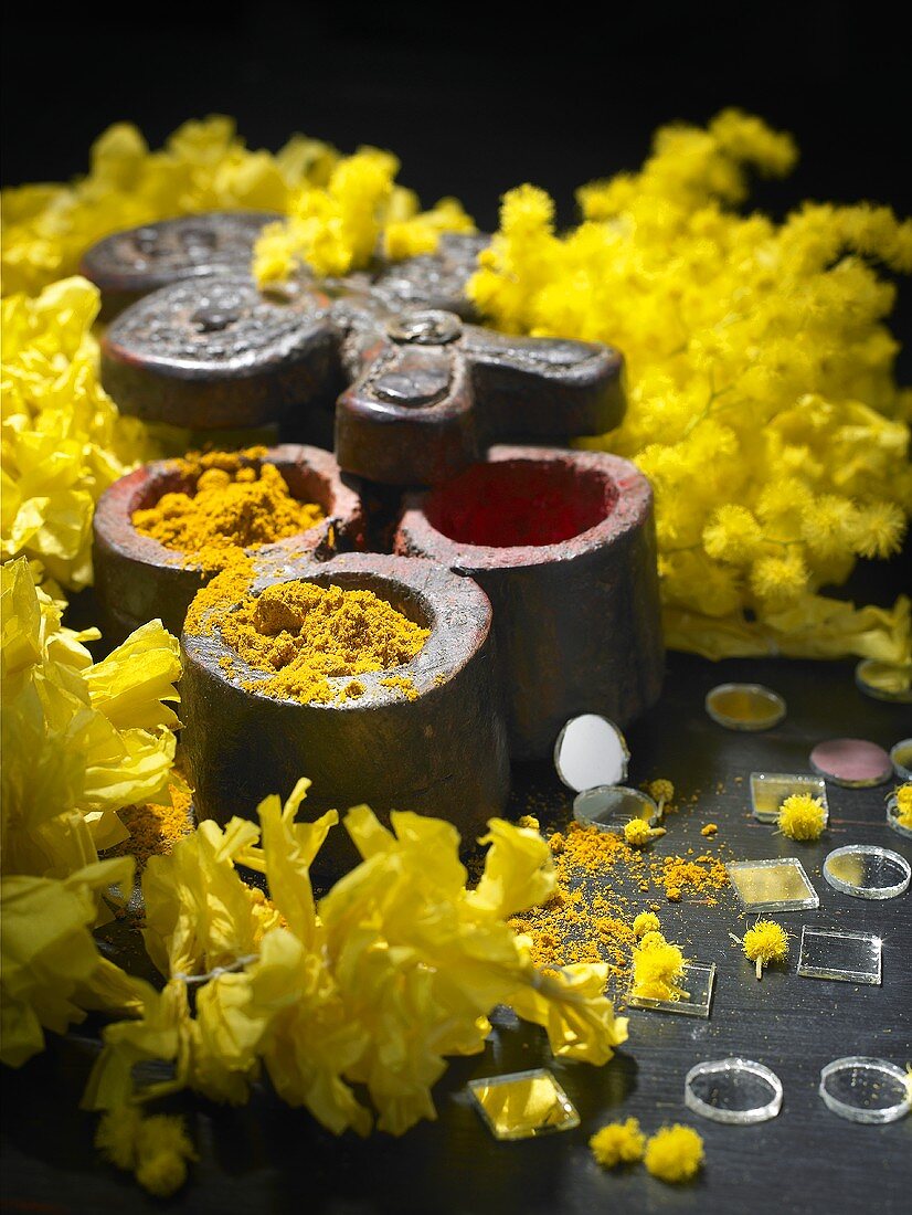 Kurkumapulver in Döschen mit gelben Blüten
