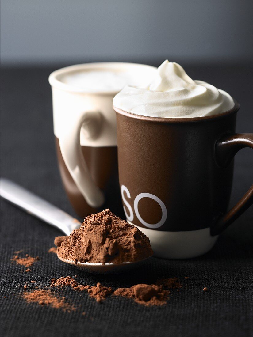 Two cups of espresso with whipped cream and cocoa powder