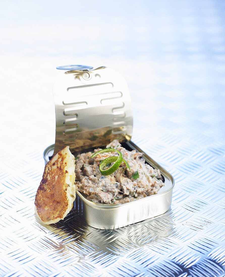 Sardine salad in a tin with a potato pancake
