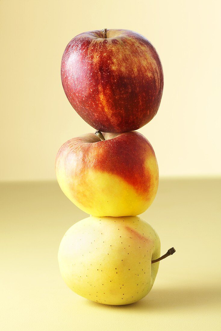 Three different apples balanced on top of each other