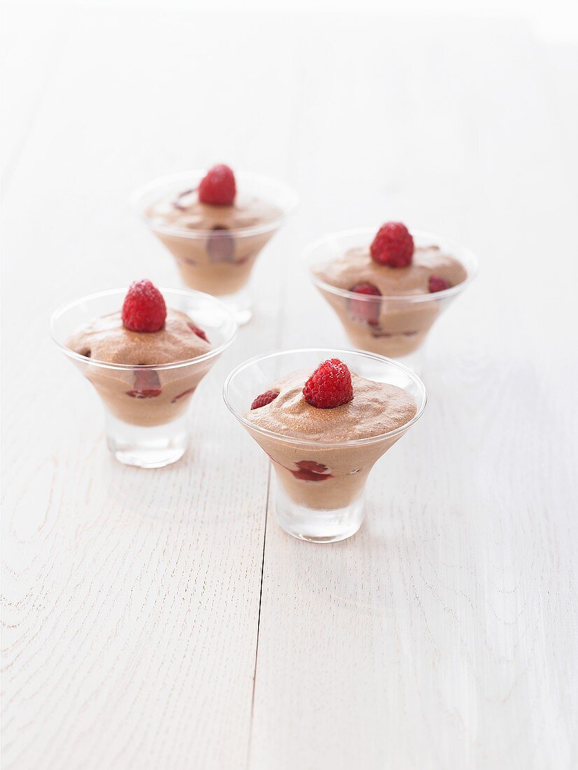 Four glasses of mousse au chocolat with fresh raspberries