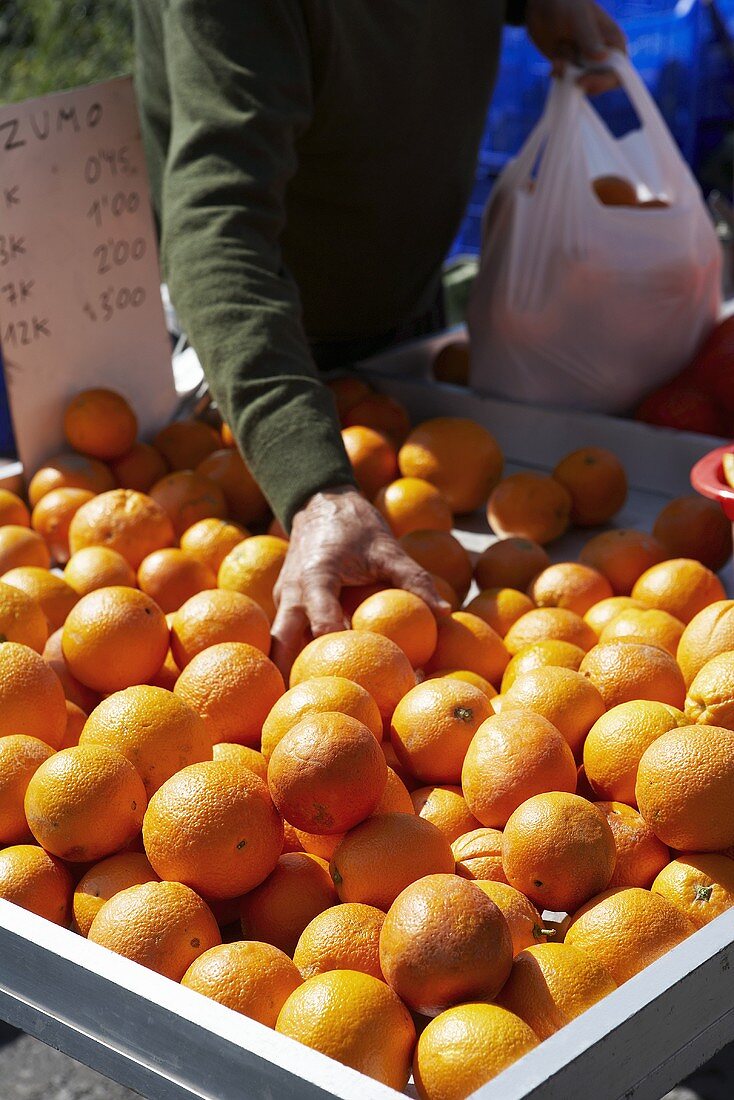 Verkäufer packt am Obststand Orangen in eine Tüte