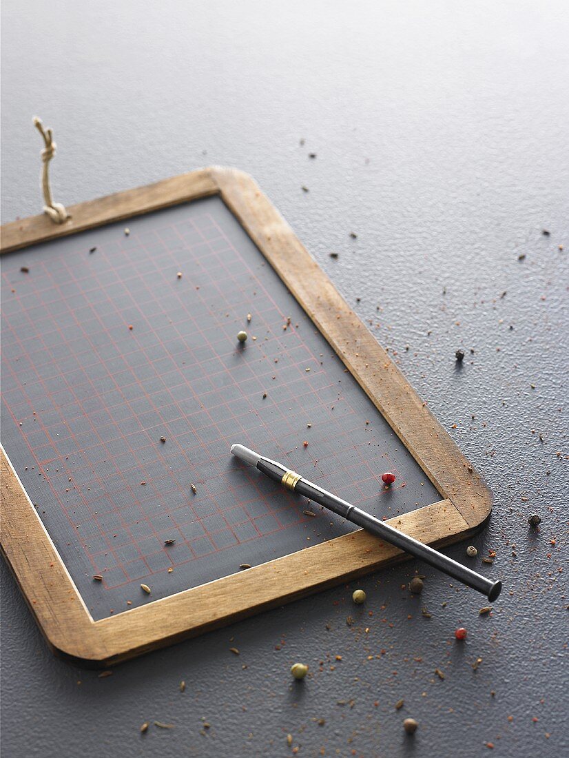 A slate board with chalk and coloured peppercorns