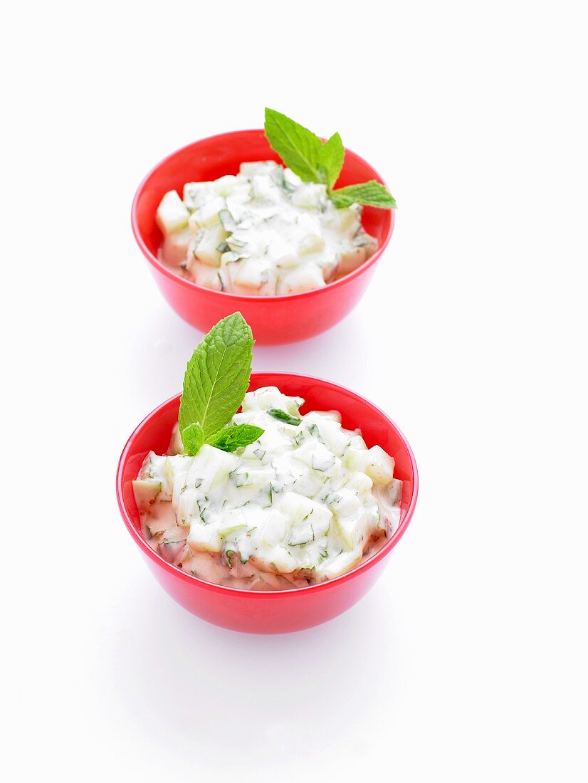 Two bowls of raita (cucumber salad with yoghurt) with mint