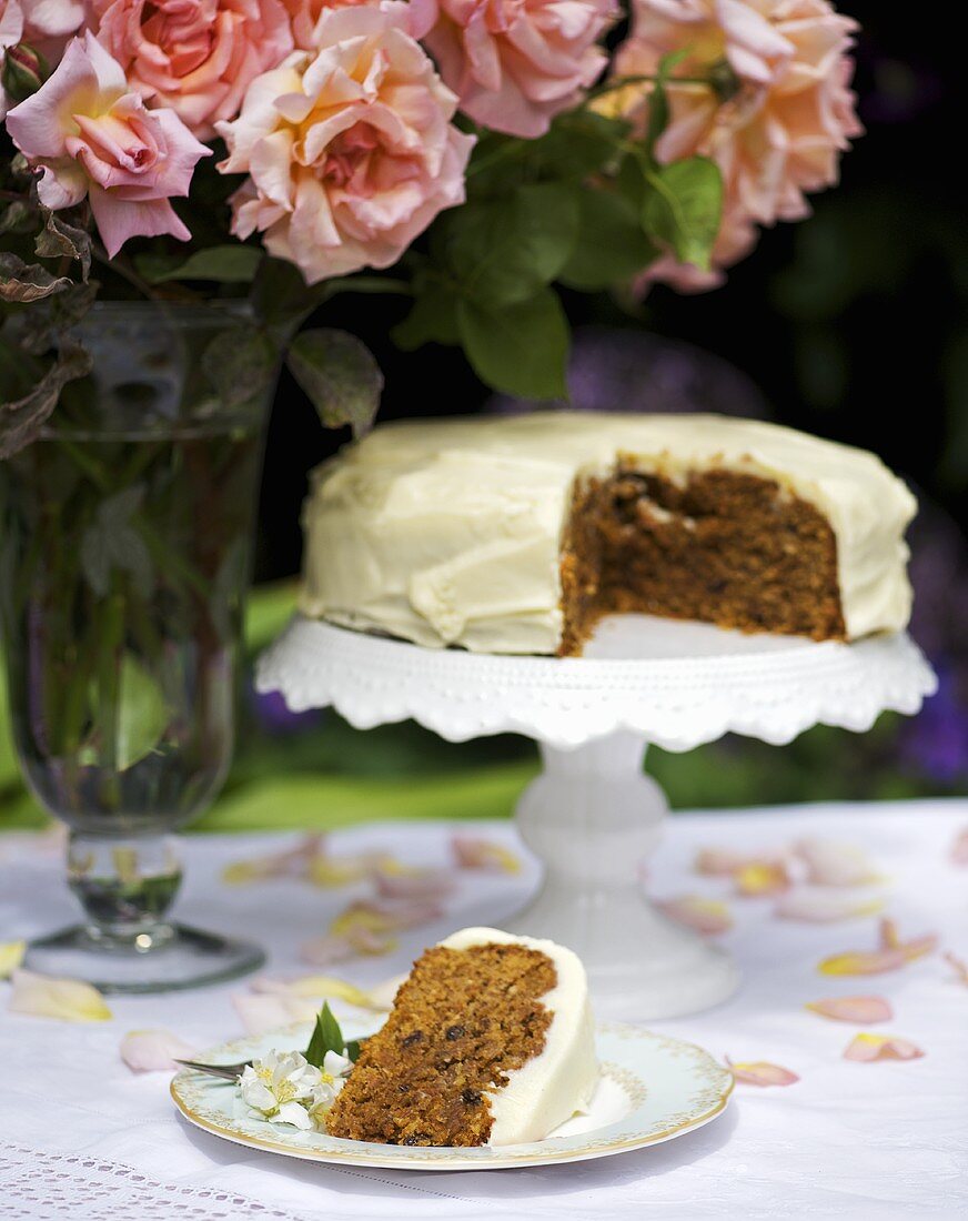 Karottenkuchen mit einem Rosenstrauss im Freien