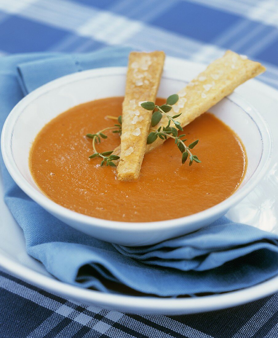 Ein Teller Karottensuppe mit frischem Thymian und Brotsticks