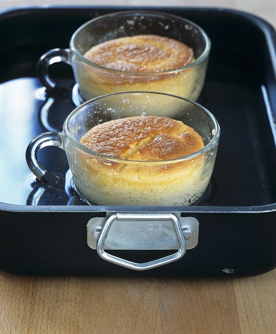 Two cups of marzipan soufflé in roasting tin with water
