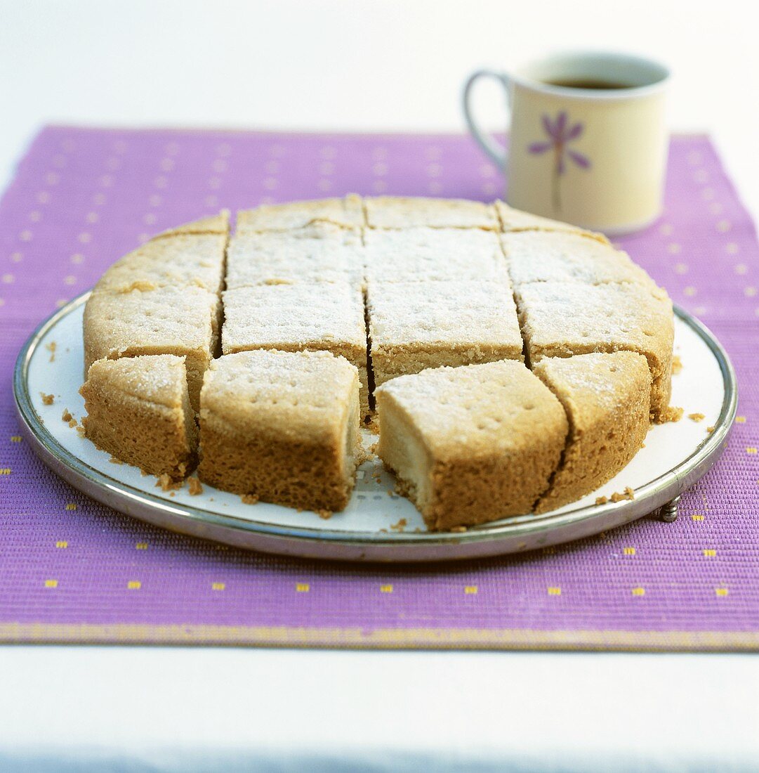 Plain cake with icing sugar, cut into pieces, on cake plate