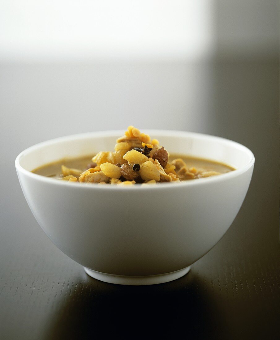 A bowl of lentil soup with chicken and raisins
