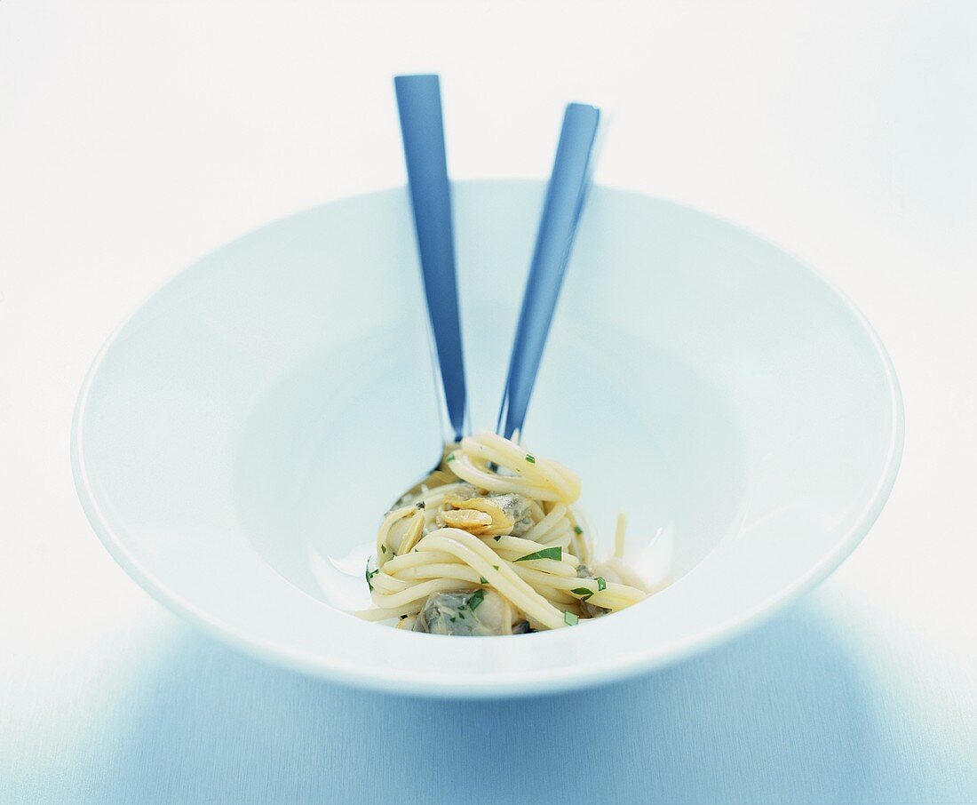 Spaghetti with shellfish on spoon and fork in dish