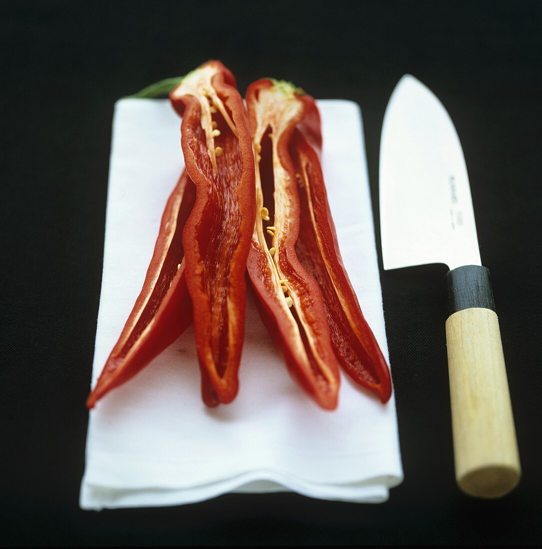 Halved chillies on a fabric napkin with knife