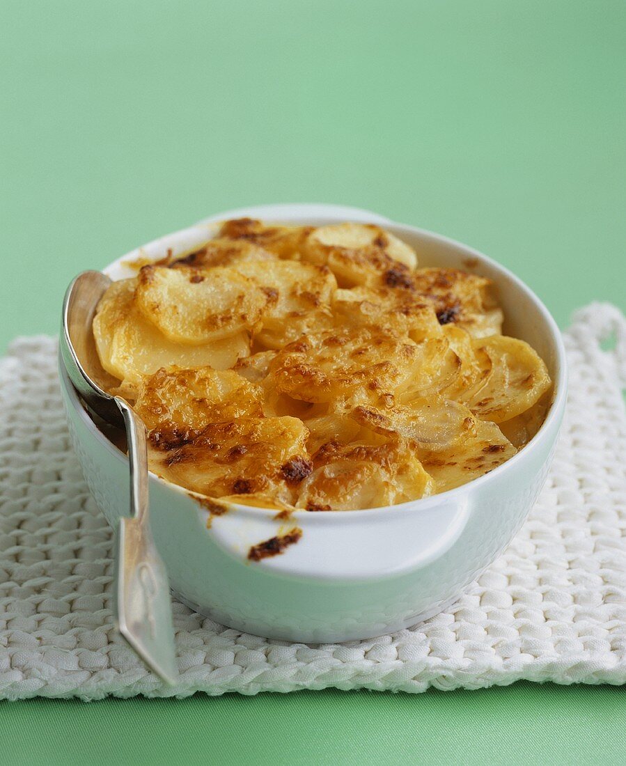 A dish of potato gratin with a spoon