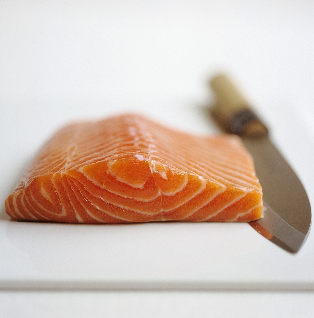 A piece of raw salmon with a knife