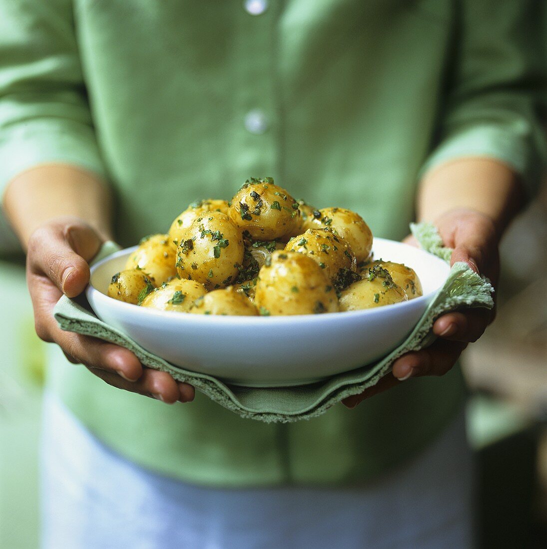 Woman carrying a dish of new potatoes with herbs