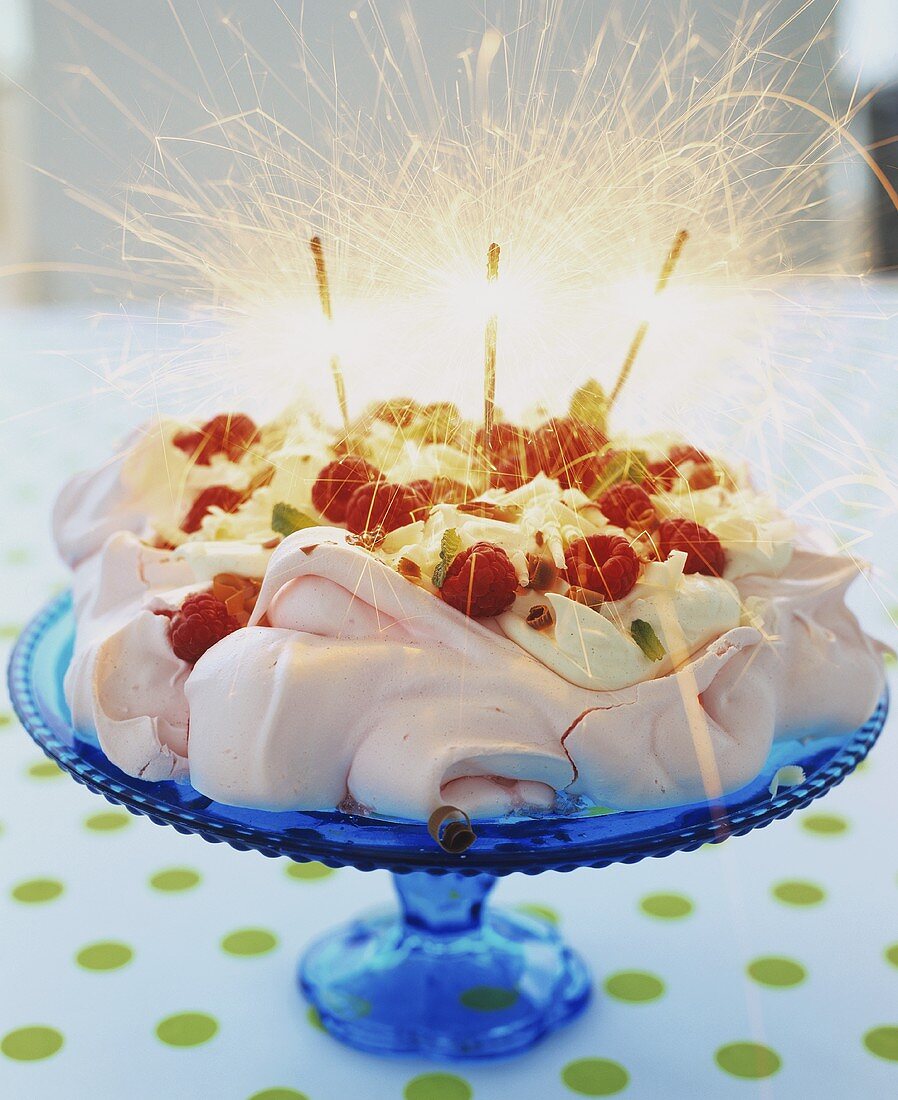 Rosafarbene Pavlova mit Himbeeren, Sahne und Wunderkerzen