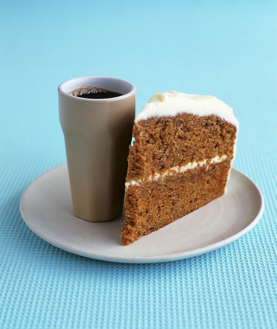 A piece of carrot cake with cream cheese icing, coffee