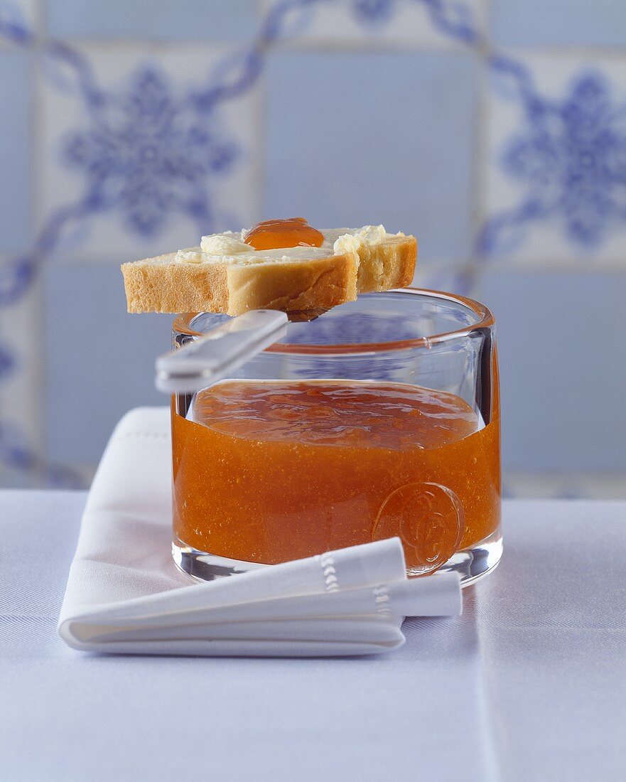 Jar of apricot jam with a slice of buttered brioche