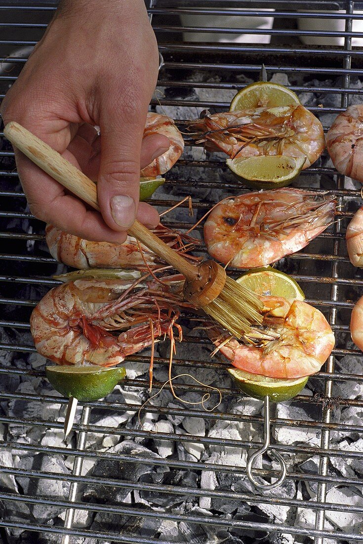 Brushing prawn kebabs on a barbecue