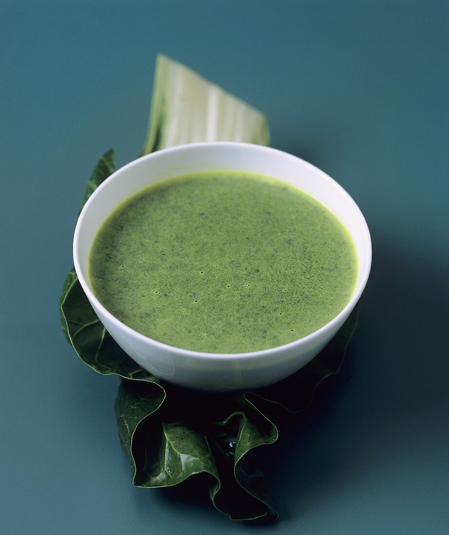 Chard and coconut soup in a bowl on a chard leaf